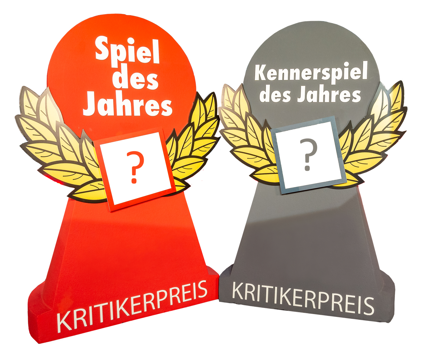 Zwei Aufsteller in Form einer roten und einer grauen Spielfigur. Auf der roten Spielfigur steht "Spiel des Jahres" und "Kritikerpreis". Auf der grauen Spielfigur steht "Kennerspiel des Jahres" und "Kritikerpreis". Beide Spielfiguren haben in der Mitte ein weißes Quadrat mit einem Fragezeichen, umgeben von einem Lorbeerkranz.